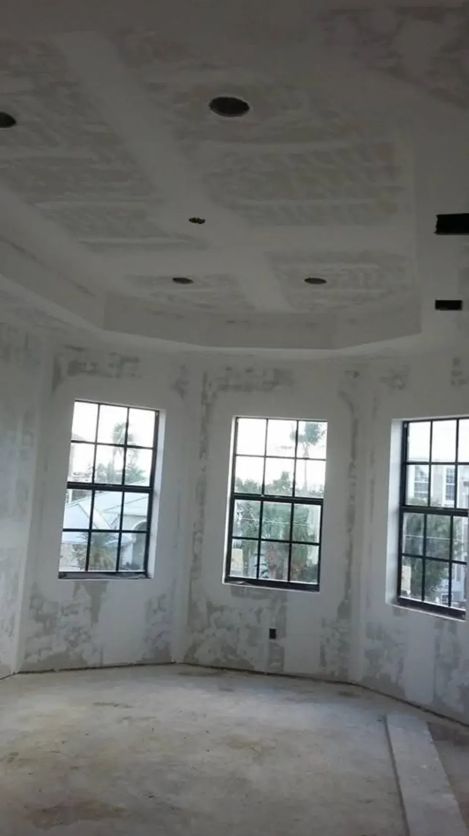Finished drywall in a bay window room with a tray ceiling and recessed lights