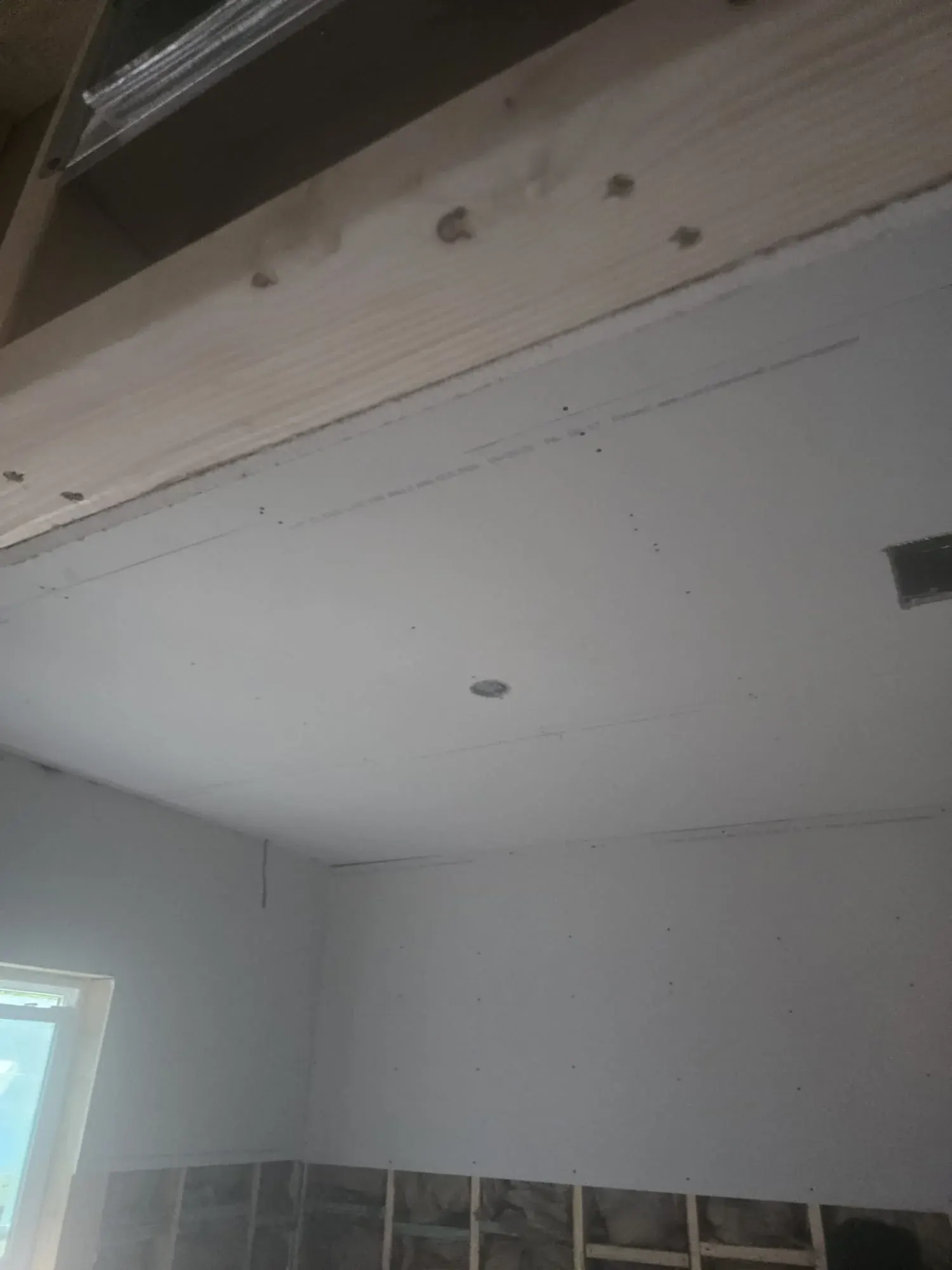 New drywall hung on a ceiling beside a framed soffit